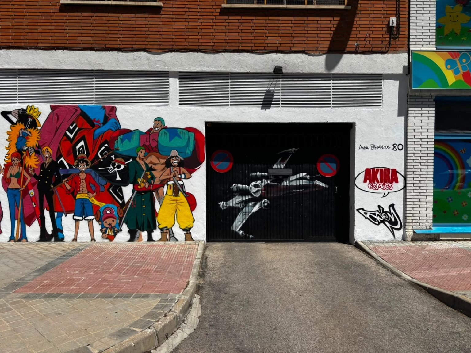 Puerta de garaje de Akira Comics pintada con una nave y el logotipo de la tienda rotulado en rojo