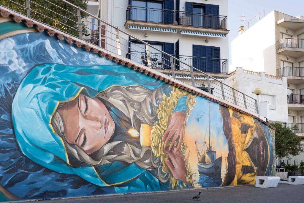 Mural «La Cala» integrado en el entorno urbano de l'Ametlla de Mar, con las viviendas del pueblo al fondo