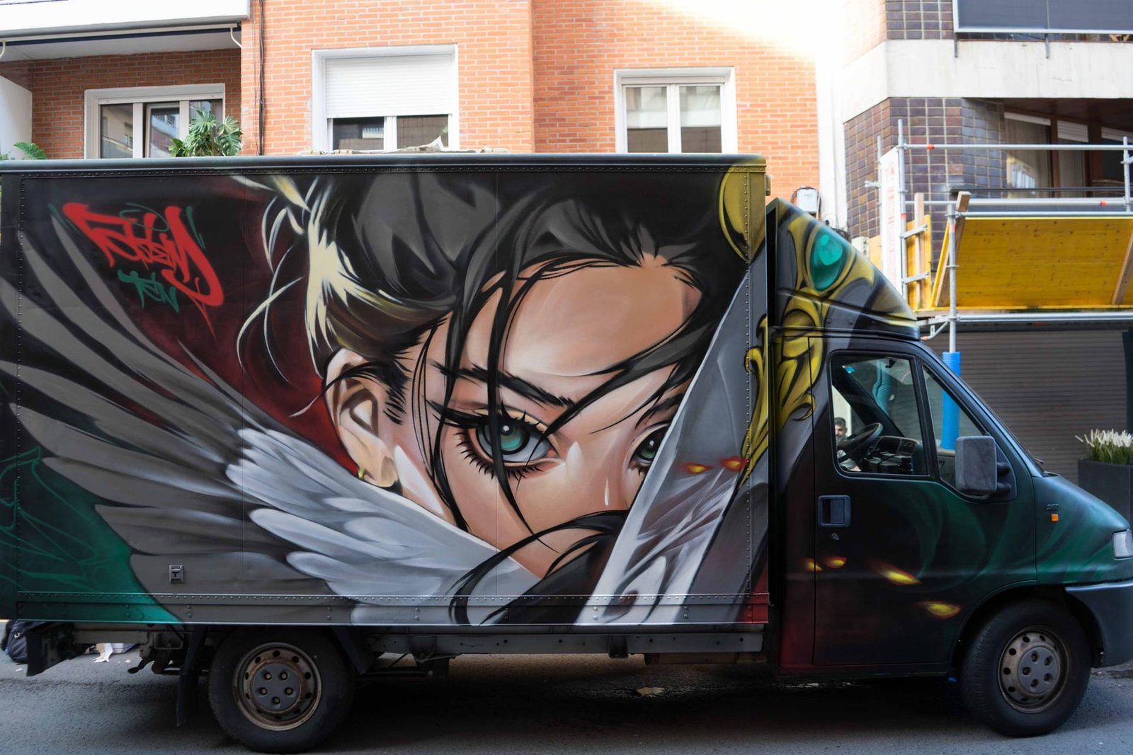 Graffiti en camión en Algorta: chica anime de ojos turquesa con alas de plumas en el lateral de la caja