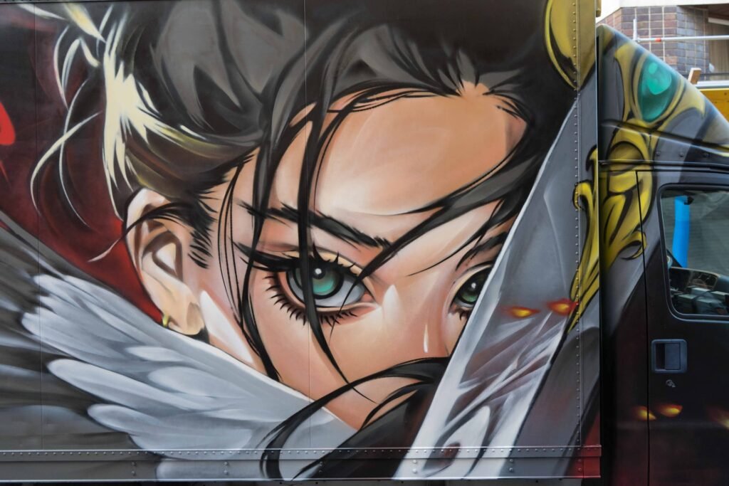 Detalle del graffiti en camión: rostro anime con mechones negros, lágrima blanca y ala de plumas