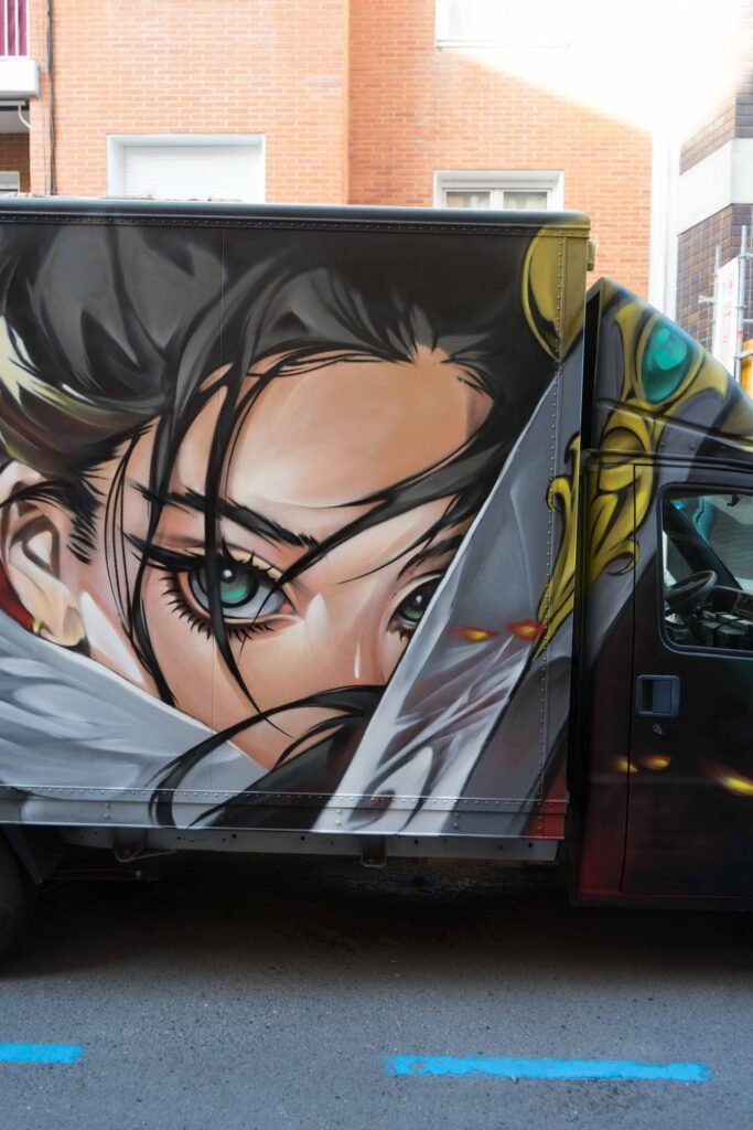 Rostro anime del graffiti en camión junto a la cabina, en una calle de Algorta durante las fiestas