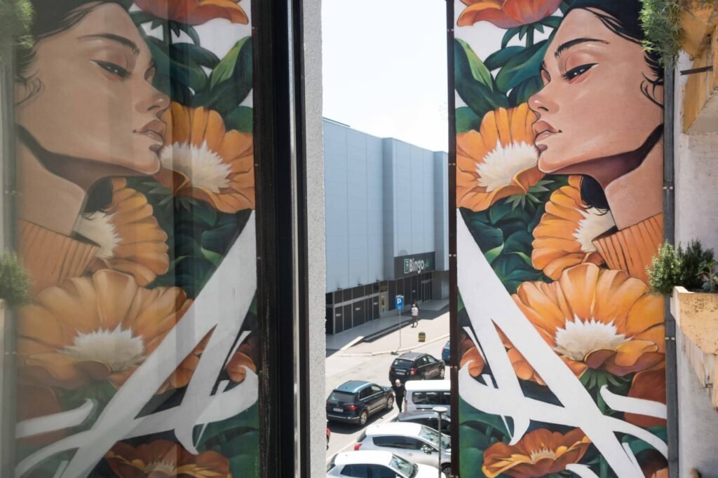 El mural Aroma de Bijeljina visto a través de la ventana de un piso vecino, con su reflejo en el cristal