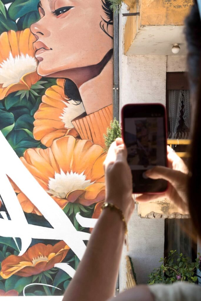 Una persona fotografía con el móvil el mural Aroma desde un balcón del edificio de al lado