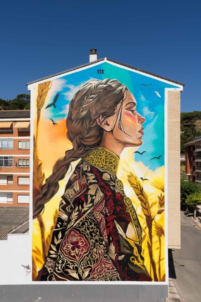 Vista completa del mural Casilda en Briviesca (Burgos): mujer con trenza, chaqueta bordada y espigas de trigo