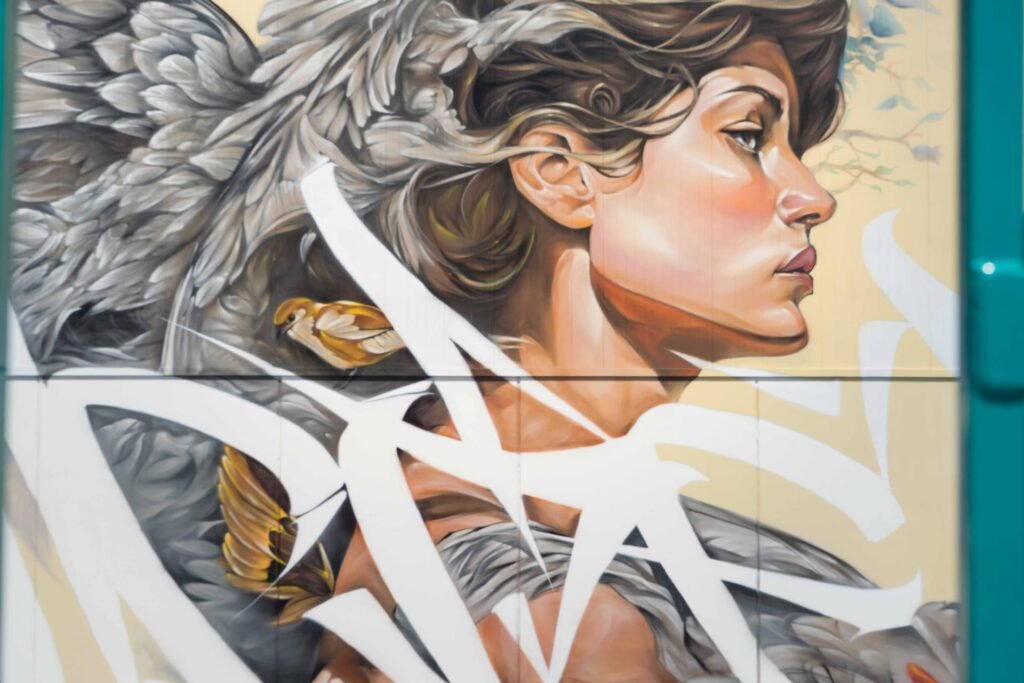 Detalle del mural Lliure: rostro de perfil con un pájaro rojo posado sobre la cabeza