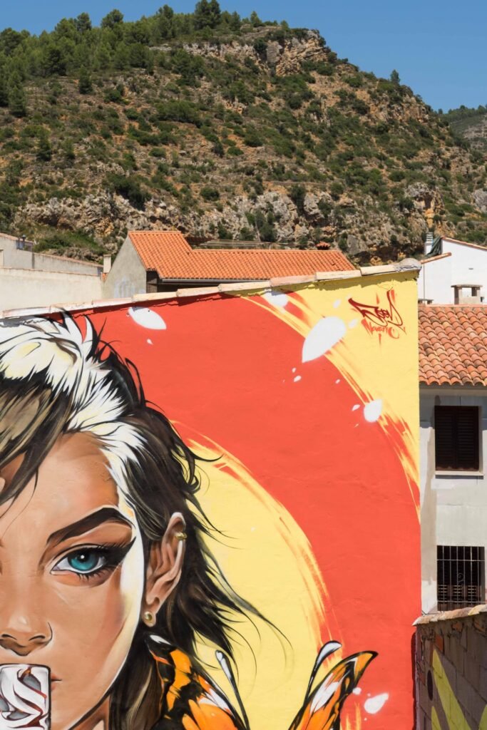 Detalle de la mirada del mural Muda de Asem Navarro sobre fondo coral y círculo amarillo