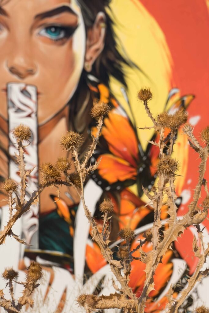 Detalle del mural Muda: rostro de mujer de ojos turquesa con una mariposa monarca en el pelo