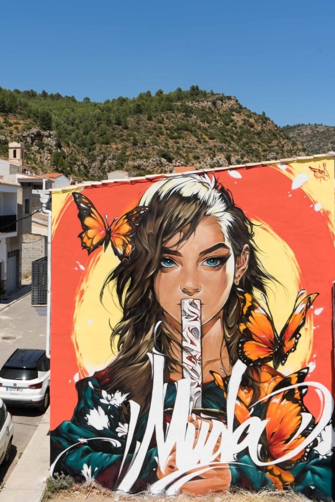 Mural Muda de Fanzara con el monte de pinos detrás, pintado en el MIAU 2026
