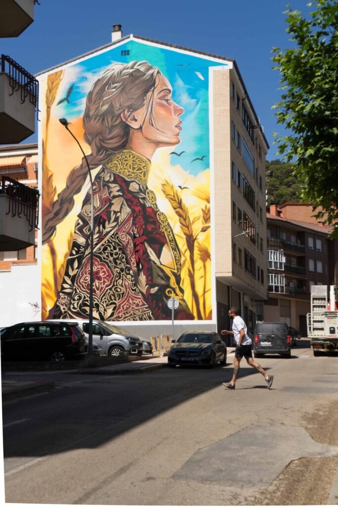 Mural de Santa Casilda en el barrio de La Taconera de Briviesca, con peatones al pie de la medianera