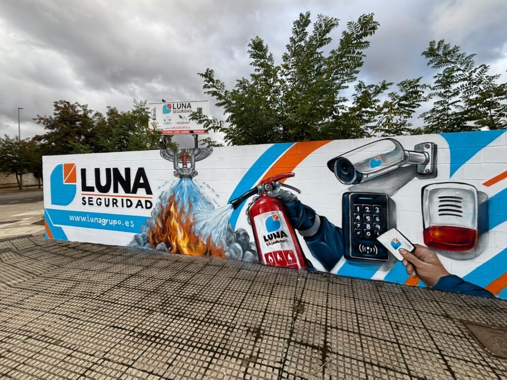 Mural corporativo de Luna Seguridad en León con extintor, cámara de videovigilancia y sirena pintados