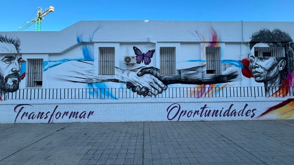 Manos estrechándose y mariposa morada en el mural del Hogar Betania, con las palabras Transformar y Oportunidades