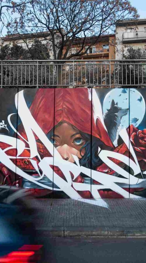 Mural de arte urbano con Caperucita Roja, lobo, serpientes y rosas rojas en Cataluña