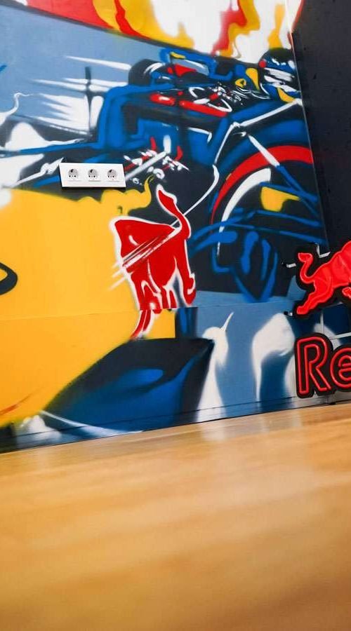 Graffiti de Red Bull con F1 y llamas en espacio interior, mural con energía y acción