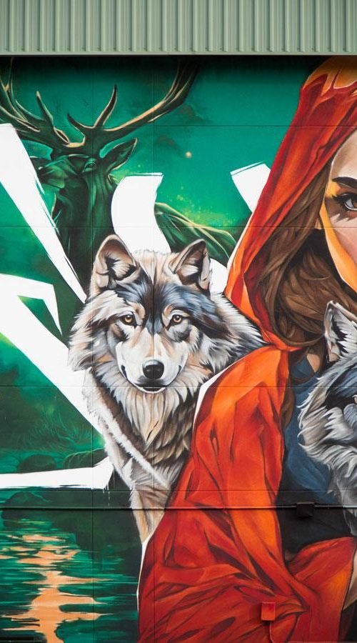 Detalle de mural escolar con ciervo, lobo y Caperucita Roja en fachada de colegio en Madrid