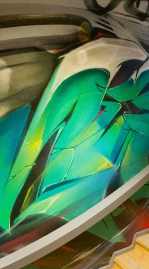 Graffiti interior con retratos y dragón en escalera de acceso a bodega