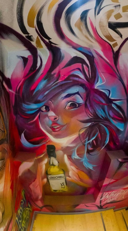 Graffiti interior con retratos y dragón en escalera de acceso a bodega