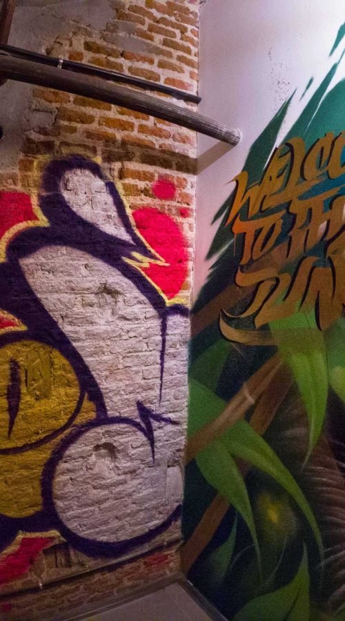 Graffiti interior con retratos y dragón en escalera de acceso a bodega
