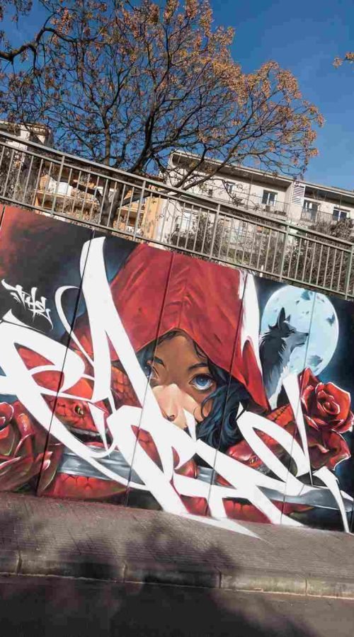 Primer plano de La Caputxeta Vermella con capucha roja en un mural graffiti exterior