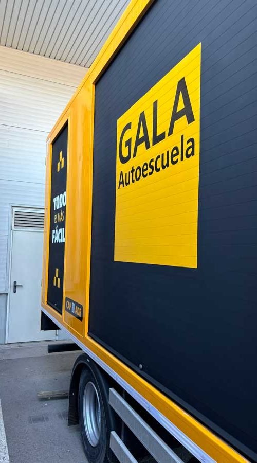 Camión amarillo y negro con rotulación de Autoescuela Gala y lema "Todo es más fácil"
