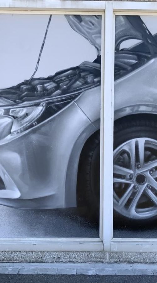 Graffiti profesional con imágenes de coches en taller Euromaster Tortosa