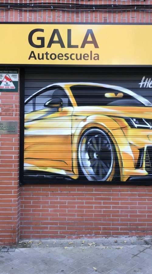 Graffiti de coche deportivo y Oso y Madroño en fachada de Autoescuela Gala
