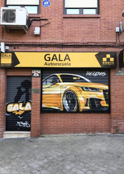 Graffiti de coche deportivo y Oso y Madroño en fachada de Autoescuela Gala