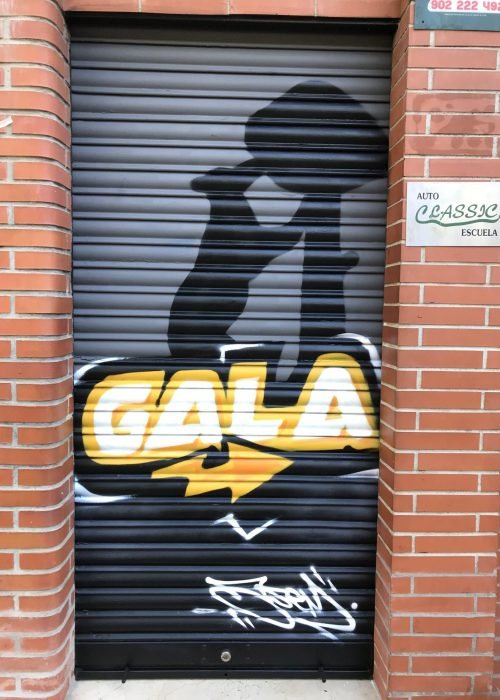 Graffiti de coche deportivo y Oso y Madroño en fachada de Autoescuela Gala