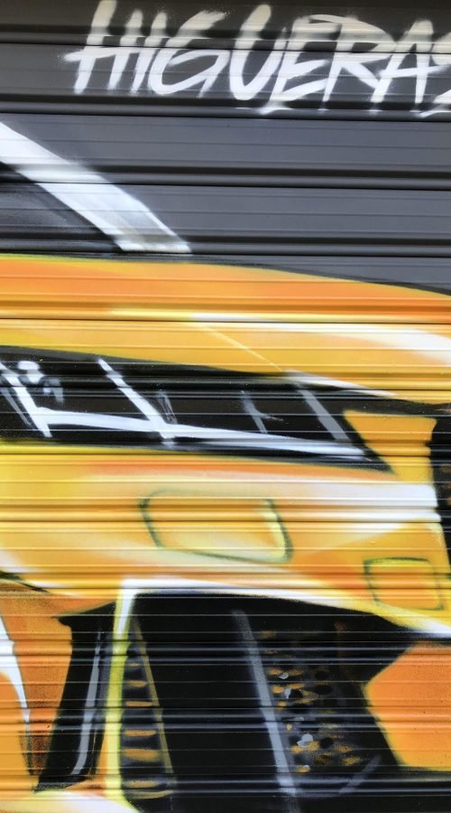 Graffiti de coche deportivo y Oso y Madroño en fachada de Autoescuela Gala