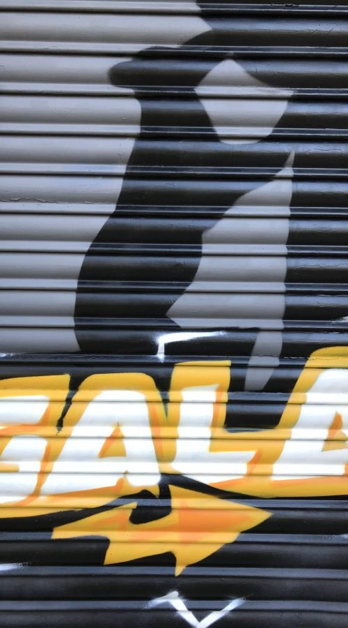 Graffiti de coche deportivo y Oso y Madroño en fachada de Autoescuela Gala