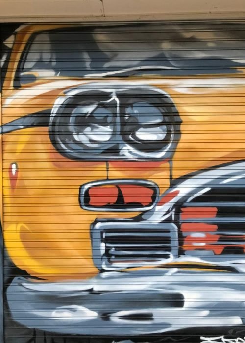 Coche clásico pintado en cierre de Autoescuela Gala Arturo Soria, graffiti realista