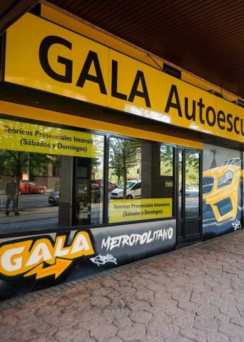 Mural con coche BMW amarillo en fachada de Autoescuela Gala Metropolitano