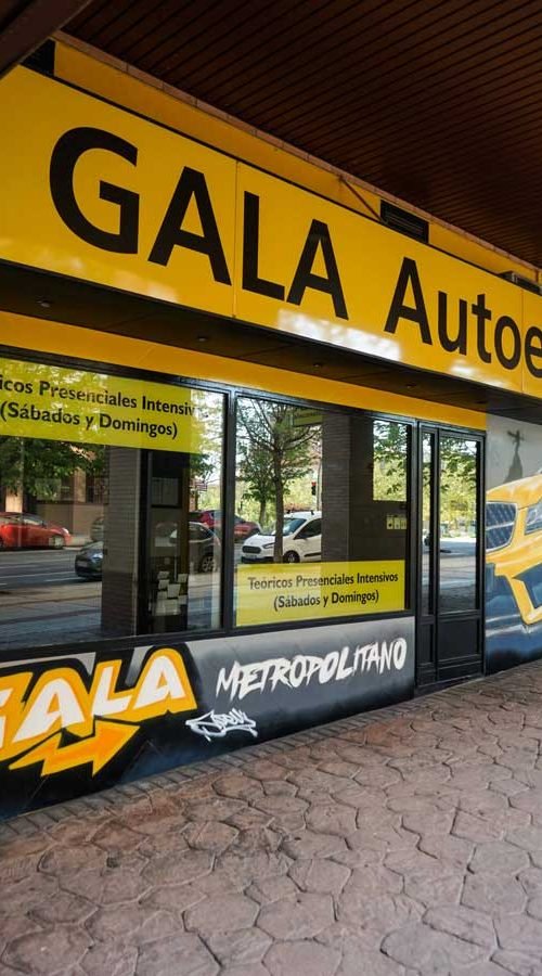 Mural con coche BMW amarillo en fachada de Autoescuela Gala Metropolitano