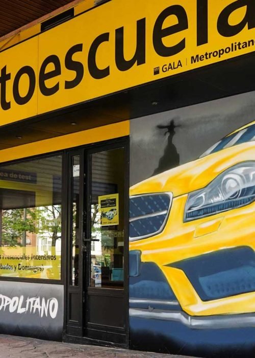 Mural con coche BMW amarillo en fachada de Autoescuela Gala Metropolitano