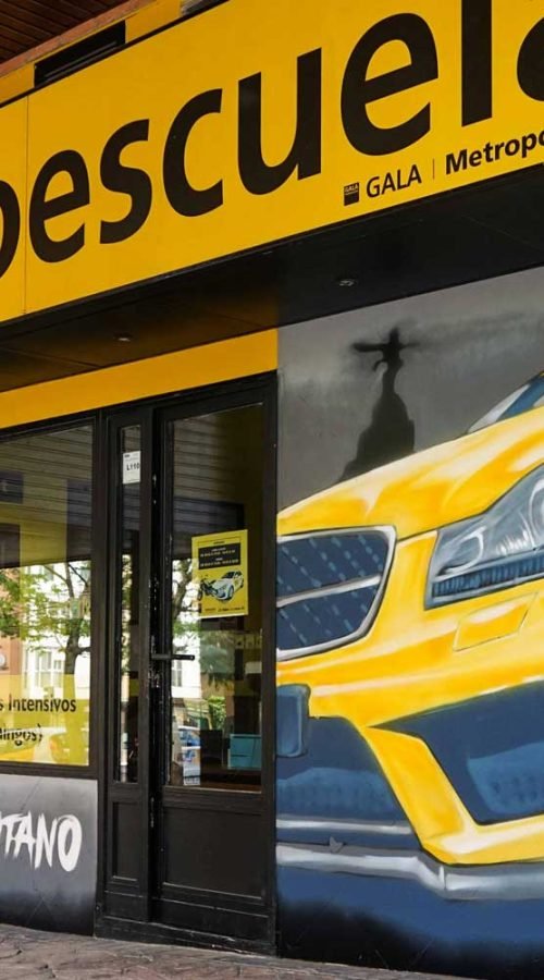 Mural con coche BMW amarillo en fachada de Autoescuela Gala Metropolitano