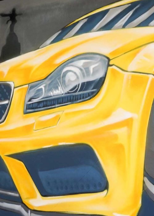 Mural con coche BMW amarillo en fachada de Autoescuela Gala Metropolitano