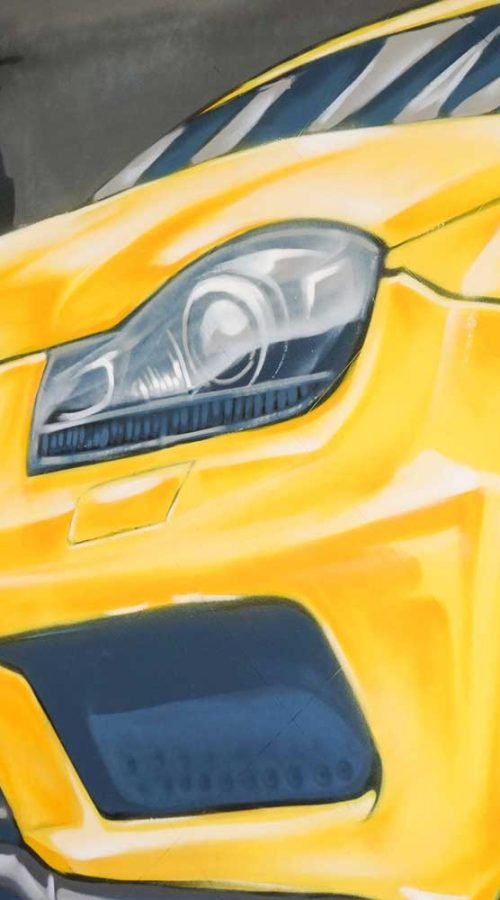 Mural con coche BMW amarillo en fachada de Autoescuela Gala Metropolitano