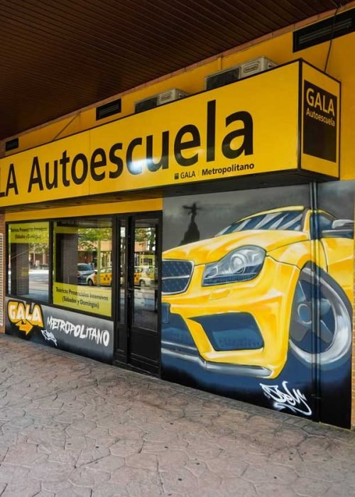 Mural con coche BMW amarillo en fachada de Autoescuela Gala Metropolitano