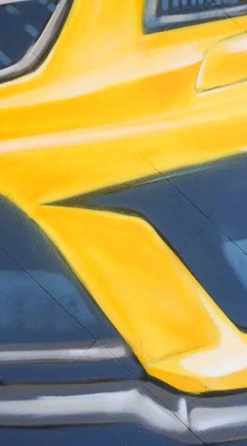 Mural con coche BMW amarillo en fachada de Autoescuela Gala Metropolitano