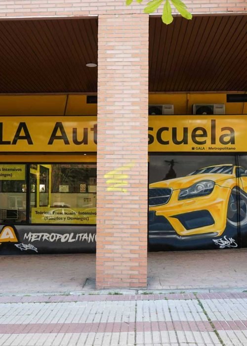 Mural con coche BMW amarillo en fachada de Autoescuela Gala Metropolitano