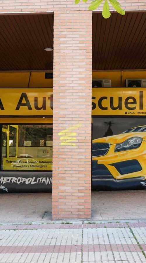 Mural con coche BMW amarillo en fachada de Autoescuela Gala Metropolitano