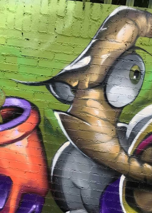 Mural graffiti de Earthworm Jim con raygun sobre fondo verde neón
