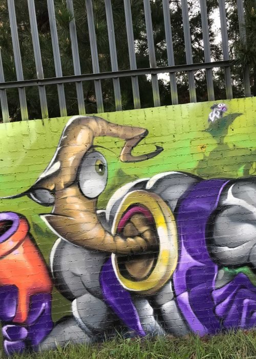 Mural graffiti de Earthworm Jim con raygun sobre fondo verde neón