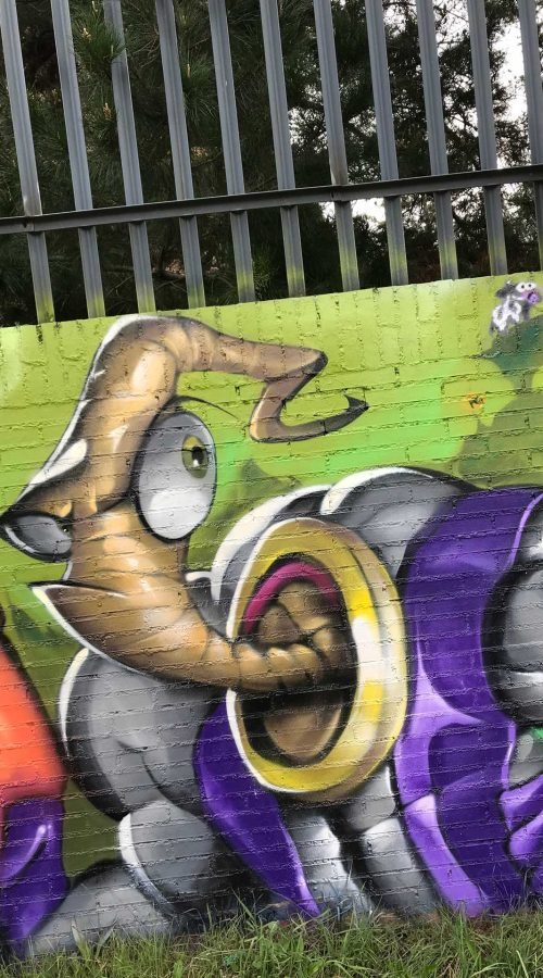 Mural graffiti de Earthworm Jim con raygun sobre fondo verde neón