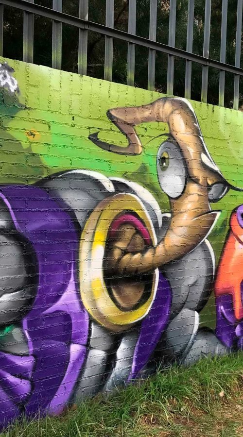 Mural graffiti de Earthworm Jim con raygun sobre fondo verde neón