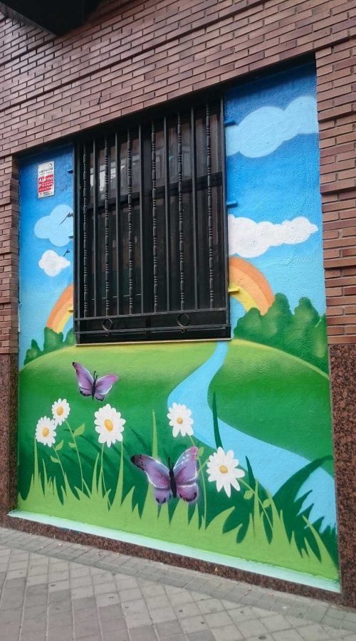 Mural infantil en guardería Nanos con globos, sol, campo y colores alegres