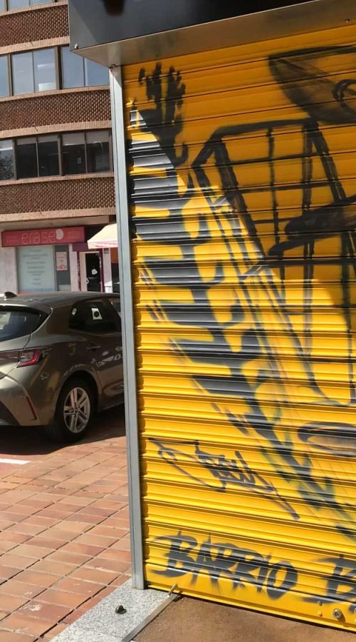 Mural con moto de carreras en cierre metálico del Barrio Blanco (Madrid), estilo urbano