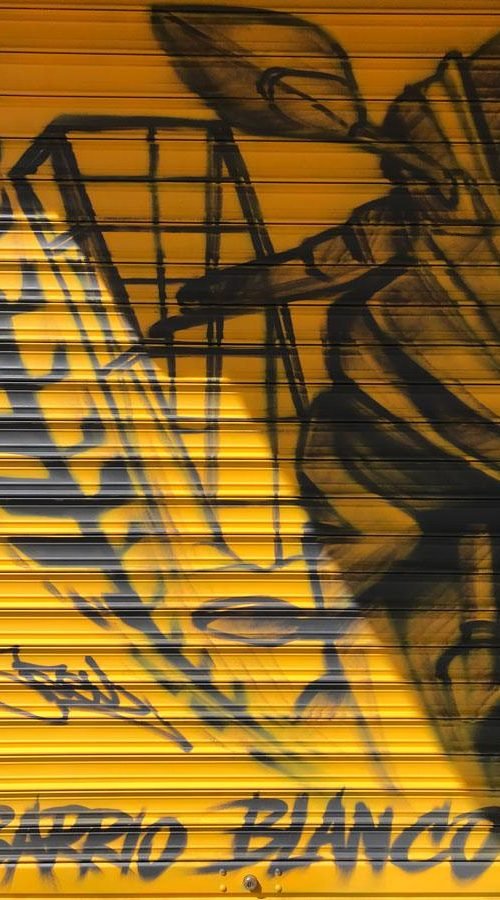 Mural con moto de carreras en cierre metálico del Barrio Blanco (Madrid), estilo urbano