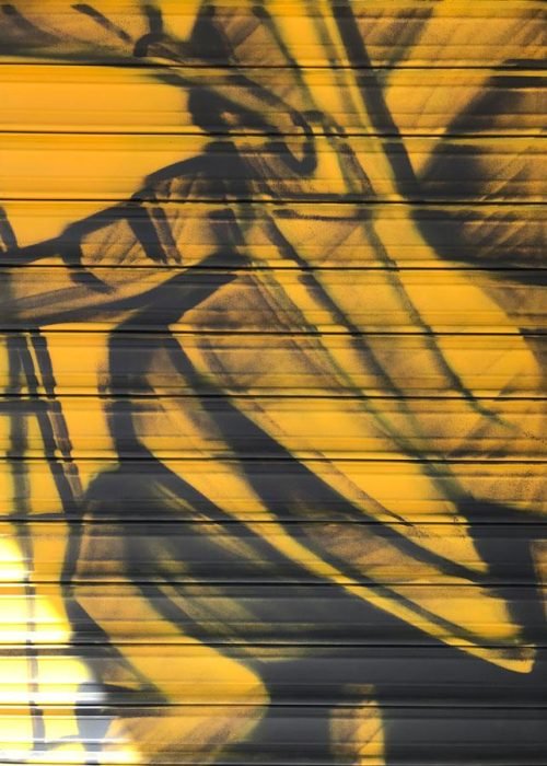 Mural con moto de carreras en cierre metálico del Barrio Blanco (Madrid), estilo urbano