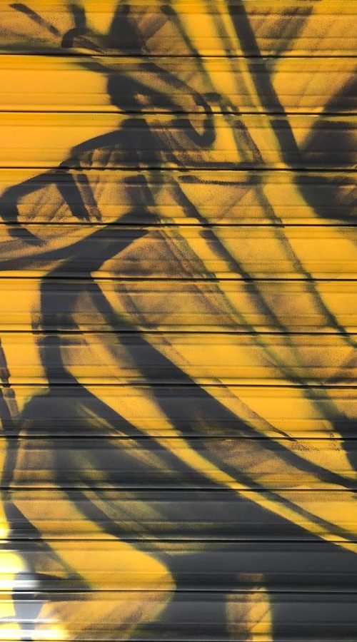 Mural con moto de carreras en cierre metálico del Barrio Blanco (Madrid), estilo urbano