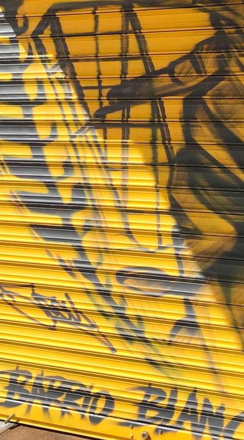 Mural con moto de carreras en cierre metálico del Barrio Blanco (Madrid), estilo urbano